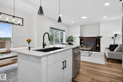Kitchen island with a matte black sink and faucet, integrated dishwasher, and white cabinetry - 9628 221 Street, Edmonton, AB 