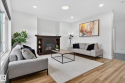 Living area featuring a dark wood-finish fireplace with built-in shelving, wood-finish flooring, recessed lighting, and large windows - 