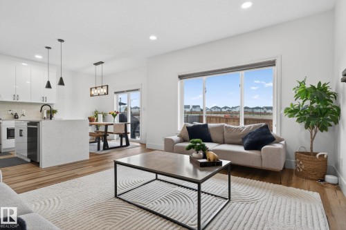 Open-concept living space featuring wood-finish flooring, recessed lighting, and a large window - 9628 221 Street, Edmonton, AB 