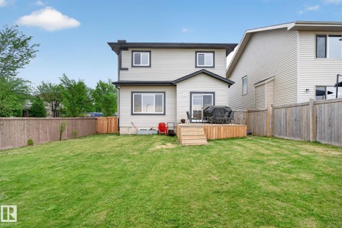 Expansive green lawn with a wooden privacy fence, a wooden deck, and sliding glass doors - 9628 221 Street, Edmonton, AB 