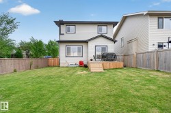 Expansive green lawn with a wooden privacy fence, a wooden deck, and sliding glass doors - 