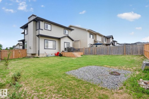 Expansive grassy backyard featuring a gravel fire pit area, wood fencing, and a raised wood deck - 9628 221 Street, Edmonton, AB 