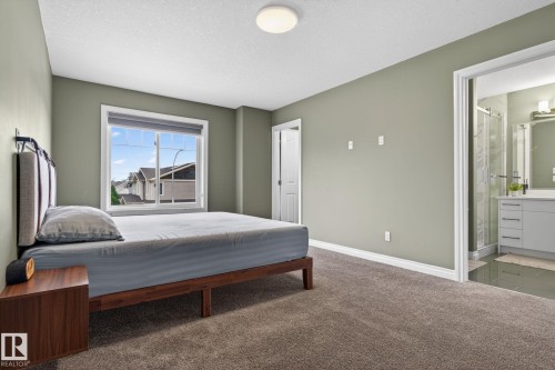 Bedroom featuring soft green walls, plush carpet flooring, and a large window with white trim - 9628 221 Street, Edmonton, AB 