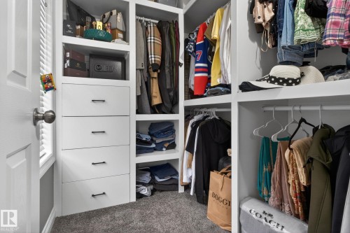 Custom closet system featuring white built-in shelving, multiple hanging rods, and integrated drawers with dark hardware - 9628 221 Street, Edmonton, AB 