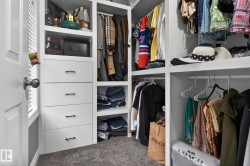 Custom closet system featuring white built-in shelving, multiple hanging rods, and integrated drawers with dark hardware - 