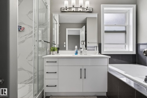Bathroom featuring a white vanity with ample storage, a framed mirror, and a sleek light fixture - 9628 221 Street, Edmonton, AB 