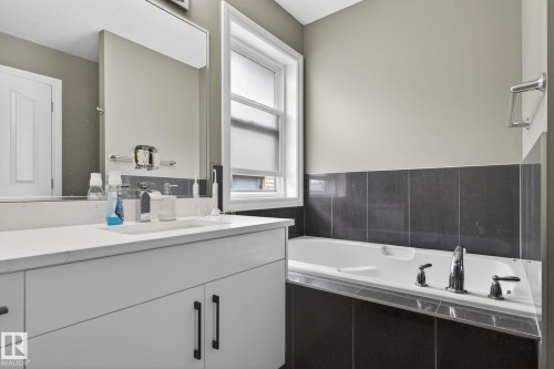 Bathroom featuring a white vanity with integrated sink, white countertop, and dark-finish hardware - 9628 221 Street, Edmonton, AB 
