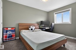 Carpeted room featuring a white-framed window, neutral painted walls, a wood-finish bed frame with an integrated headboard, and a white ceiling with a flush-mount light fixture - 