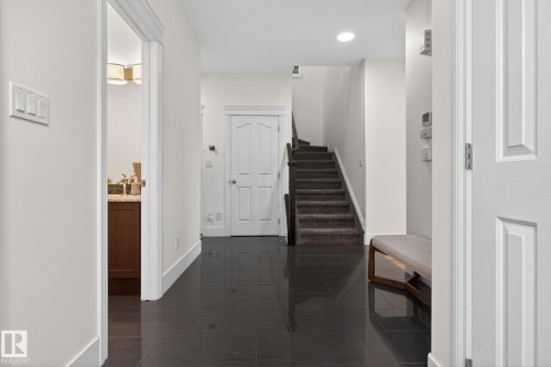 Entryway featuring dark tile flooring, a carpeted staircase, a white paneled door, and recessed lighting - 9628 221 Street, Edmonton, AB 