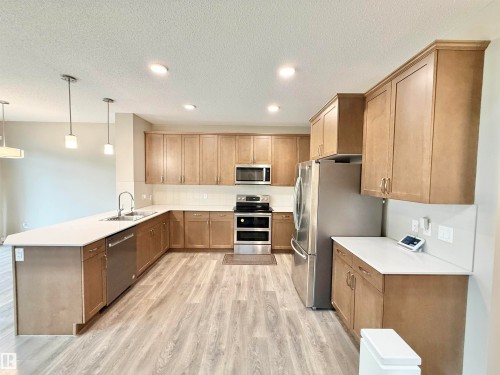Spacious kitchen featuring light wood-finish cabinetry, stainless steel appliances, and light-toned countertops - 22519 96 Avenue, Edmonton, AB 