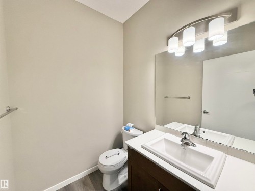 Bathroom featuring a wood-finish vanity with an integrated sink, polished chrome faucet, and a large wall-mounted mirror - 22519 96 Avenue, Edmonton, AB 