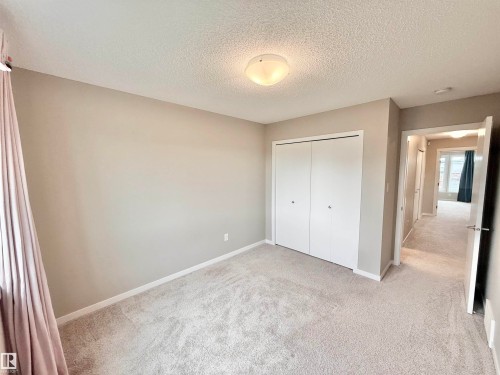 Carpeted room featuring a white bi-fold closet, neutral wall paint, white trim, and a ceiling-mounted light fixture - 22519 96 Avenue, Edmonton, AB 