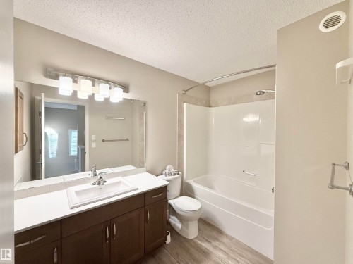 Bathroom featuring a vanity with a white countertop and dark wood-finish cabinetry, a built-in rectangular sink, and a large wall-mounted mirror - 22519 96 Avenue, Edmonton, AB 