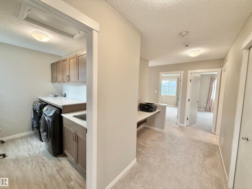 Dedicated laundry room with wood-finish flooring, light cabinetry, white countertops, and an integrated sink - 22519 96 Avenue, Edmonton, AB 