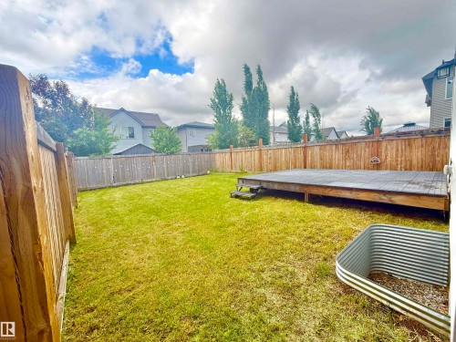 Expansive backyard featuring a large wooden deck, manicured lawn, and privacy fencing - 22519 96 Avenue, Edmonton, AB 