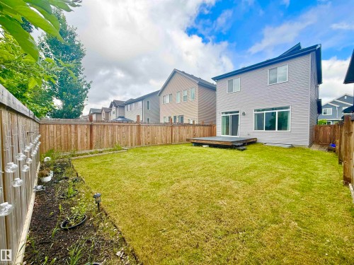 Private fenced backyard featuring a wooden deck, sliding glass door access, and a garden bed - 22519 96 Avenue, Edmonton, AB 
