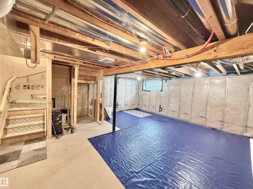 Unfinished lower level featuring exposed ceiling joists and ductwork, a carpeted staircase, framed wall sections, and insulated exterior walls - 22519 96 Avenue, Edmonton, AB 