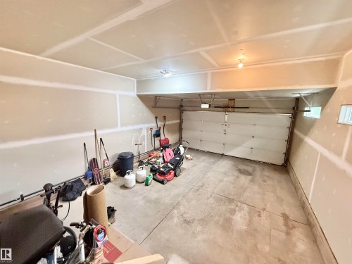 Spacious garage featuring a concrete floor, overhead lighting, and an automatic garage door - 22519 96 Avenue, Edmonton, AB 