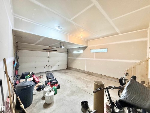 Two-car garage featuring a roll-up door, concrete flooring, and an upper transom window - 22519 96 Avenue, Edmonton, AB 