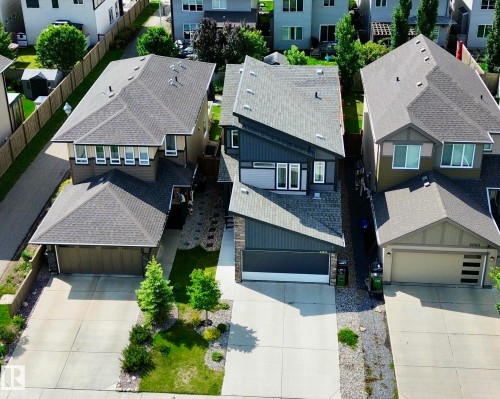 Contemporary home exterior featuring a dark gray and light gray siding combination with stone accents, a multi-pitch roofline, and an attached two-car garage - 22519 96 Avenue, Edmonton, AB 