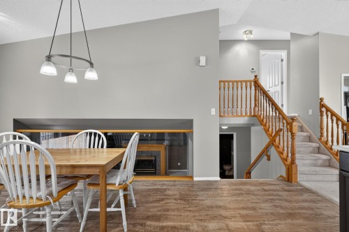 Vaulted ceiling featuring a contemporary chandelier, wood-finish flooring, and a multi-level staircase with wood railings - 6225 159A Avenue, Edmonton, AB 