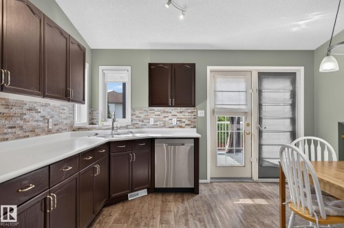 Kitchen featuring rich cabinetry, light countertops, and a full tile backsplash - 6225 159A Avenue, Edmonton, AB 