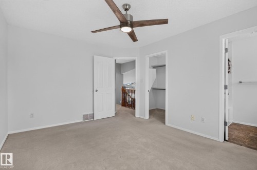 Carpeted room featuring a ceiling fan with integrated lighting, neutral wall paint, white trim, and a panel door - 6225 159A Avenue, Edmonton, AB 