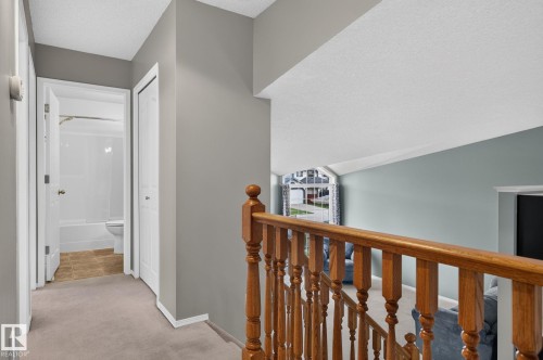 Upper-level hallway with light gray walls, carpet flooring, and a wooden banister - 6225 159A Avenue, Edmonton, AB 