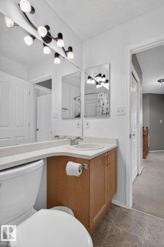 Bathroom featuring a corner vanity with a light-toned countertop, integrated sink, and wood-finish cabinetry - 6225 159A Avenue, Edmonton, AB 