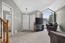 Vaulted ceiling living area featuring a large arched window with grid details, light gray wall paint, and a mirrored closet - 6225 159A Avenue, Edmonton, AB 