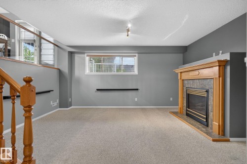Lower level living area featuring a prominent fireplace with a wood-finish mantel and stone-look surround - 6225 159A Avenue, Edmonton, AB 