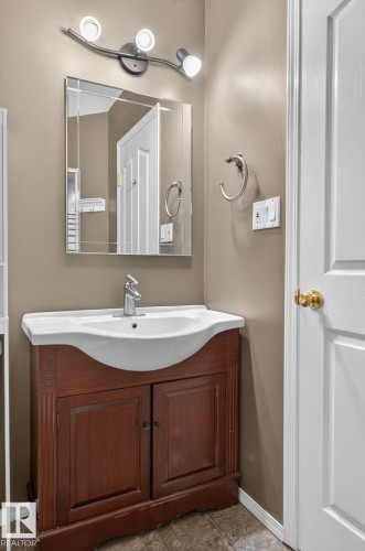 Vanity with a white ceramic basin sink, single-handle chrome faucet, and a dark wood-finish cabinet - 6225 159A Avenue, Edmonton, AB 