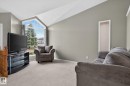 Vaulted ceilings enhance the living space, featuring a large trapezoidal window, light-colored carpeting, and neutral wall tones - 6225 159A Avenue, Edmonton, AB 
