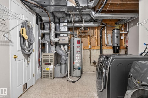 Utility area featuring a side-by-side washer and dryer set, water heater, and furnace system - 6225 159A Avenue, Edmonton, AB 