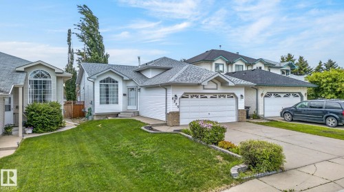 White vinyl siding exterior with an attached two-car garage, arched front window, concrete driveway, and established front landscaping - 6225 159A Avenue, Edmonton, AB 
