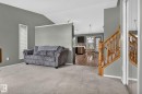Carpeted living area featuring vaulted ceilings, a vertical window with blinds, and a partial wall dividing the space - 6225 159A Avenue, Edmonton, AB 