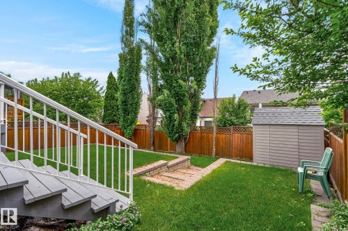 Expansive backyard featuring a manicured lawn, wood fencing, mature trees, and a functional storage shed - 6225 159A Avenue, Edmonton, AB 