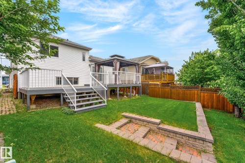 Expansive backyard featuring a manicured lawn, a multi-level deck with white railings, and a privacy fence - 6225 159A Avenue, Edmonton, AB 