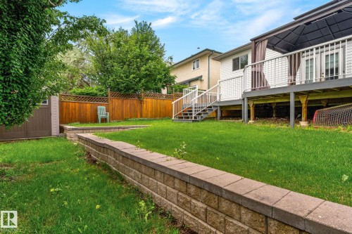 Spacious backyard featuring a multi-level layout with a retaining wall, mature trees, a privacy fence, and a storage shed - 6225 159A Avenue, Edmonton, AB 