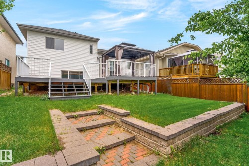 Rear exterior featuring a white siding finish, a multi-level deck with white railings, and a lower-level grass yard - 6225 159A Avenue, Edmonton, AB 