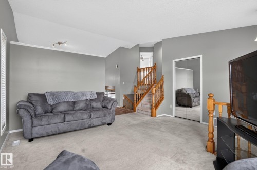 Carpeted living area featuring vaulted ceilings, track lighting, and a window with horizontal blinds - 6225 159A Avenue, Edmonton, AB 