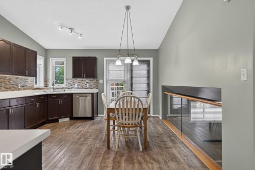 Open-concept kitchen and dining area featuring dark wood cabinetry, a tiled backsplash, and stainless steel appliances - 6225 159A Avenue, Edmonton, AB 