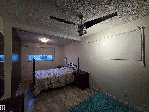 Bedroom featuring wood-finish flooring, a ceiling fan with integrated lighting, and a window with a roller blind - 2514 149 Avenue, Edmonton, AB 