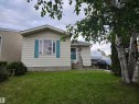 Front exterior featuring horizontal siding, a central window with decorative blue shutters, and a covered entry - 2514 149 Avenue, Edmonton, AB 