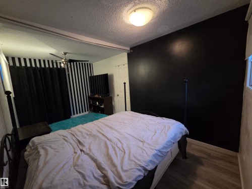 Room featuring a black accent wall, wood-finish flooring, and a ceiling fan - 2514 149 Avenue, Edmonton, AB 