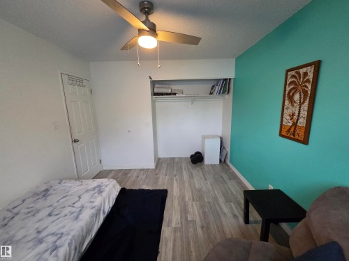 Room featuring wood-finish flooring, a ceiling fan with integrated lighting, and a closet with shelving - 2514 149 Avenue, Edmonton, AB 