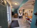 Entryway featuring wood-finish flooring, a decorative front door with transom window, and an open concept layout with an integrated living space and dining area - 2514 149 Avenue, Edmonton, AB 