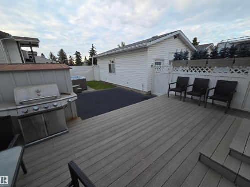 Expansive outdoor living area featuring a multi-level composite deck, white lattice privacy fence, and hot tub with exterior steps - 2514 149 Avenue, Edmonton, AB 