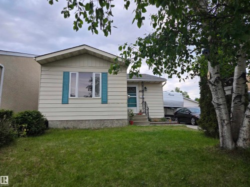 Front exterior featuring horizontal siding, a central window with decorative blue shutters, and a covered entry - 2514 149 Avenue, Edmonton, AB 