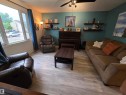 Living area featuring light wood-finish flooring and a ceiling fan with integrated lighting - 2514 149 Avenue, Edmonton, AB 